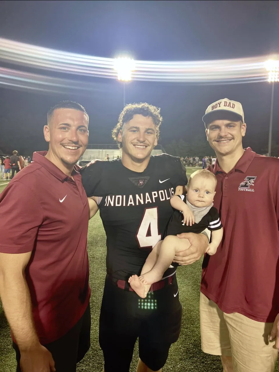 Koby, KJ holding Leland, and Kinnon together on a football field